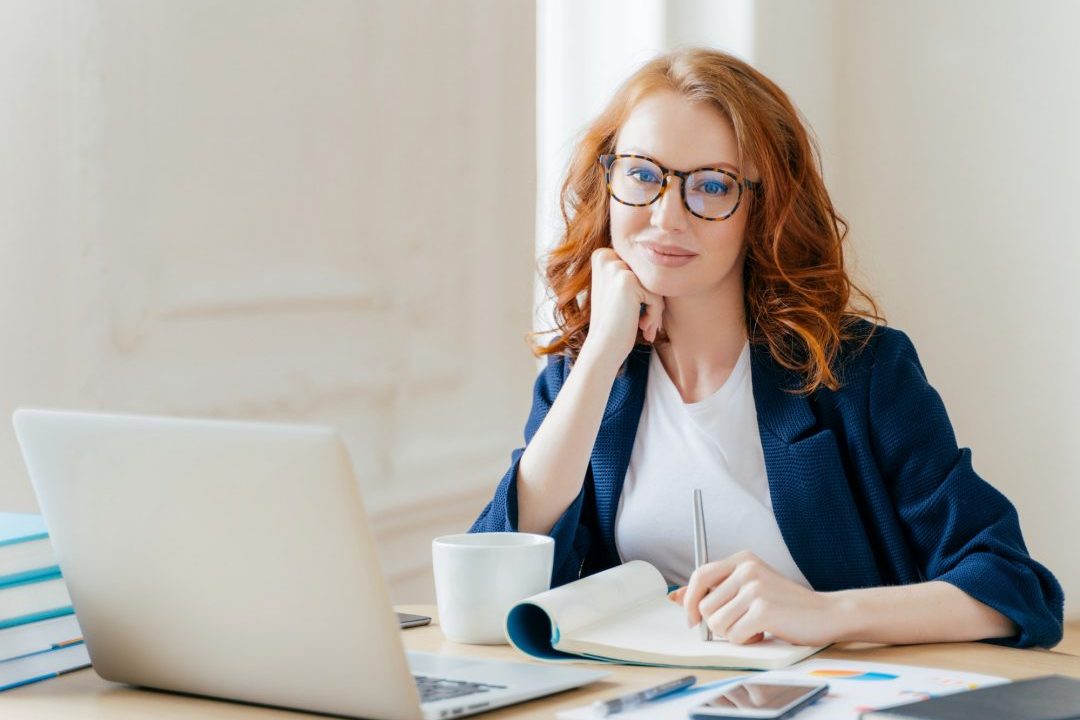 redhead-curly-woman-office-worker-analyzes-data-makes-accounting-report-poses-in-coworking-office.jpg